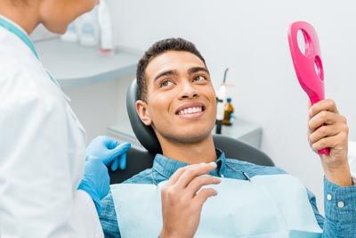 patient looking in the mirror after getting his teeth cleaned at Smile Design Center