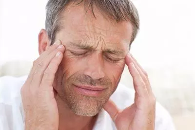 man holding his head due to a migraine from TMJ issues